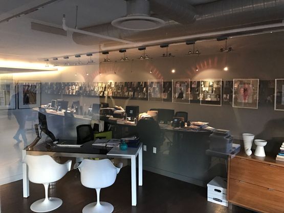 An agency office seen through glass, comp cards along the far wall.