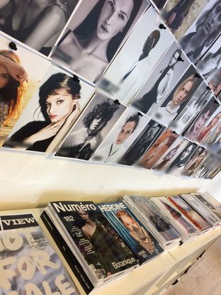 Comp cards pinned to an agency wall above a shelf of fashion magazines, names blurred.