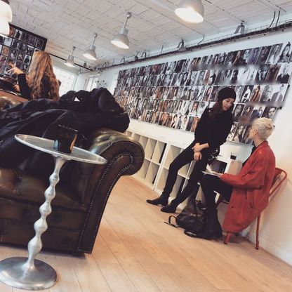 People in conversation in an agency lounge, beneath a wall of comp cards.